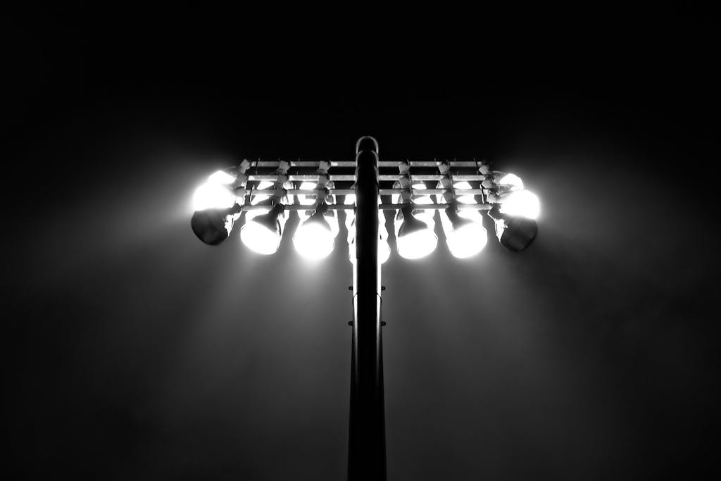 Black and white photo of stadium floodlights illuminating the night sky in Boston.