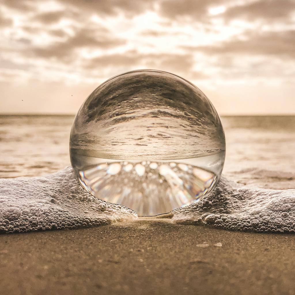 A crystal ball resting on Bonita Springs beach reflecting ocean waves at sunset.